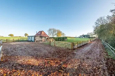 a dirt road with a fence and a barn at Bumblebee Cottage in Barnham
