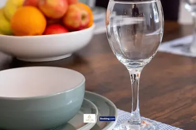 a wine glass sitting on a table with a bowl of fruit at Centrally Located 3 Bedroom House By Trinity Stays Short Lets & Serviced Accommodation Cambridge in Cambridge