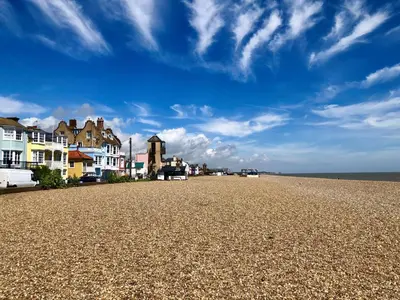a beach with houses and a blue sky and clouds at Admiral Cottage in Woodbridge
