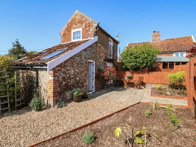 a brick cottage with an awning and a patio at Admiral Cottage in Woodbridge