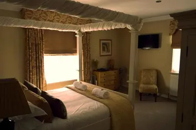 a bedroom with a canopy bed and a chair at Le Bouchon Brasserie & Hotel in Maldon