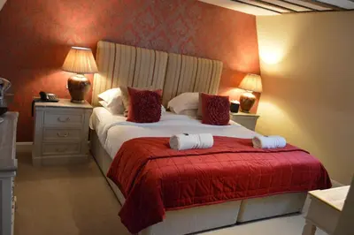a bedroom with a bed with white sheets and red blanket at Le Bouchon Brasserie & Hotel in Maldon