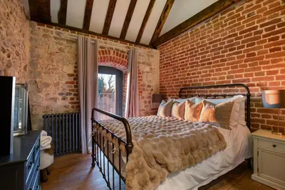 a bedroom with a brick wall and a bed at Toll Barn, St Osyth Priory in Colchester