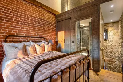 a bed in a room with a brick wall at Toll Barn, St Osyth Priory in Colchester