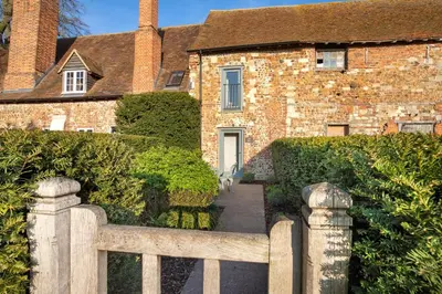 a brick house with a wooden fence in front of it at Toll Barn, St Osyth Priory in Colchester
