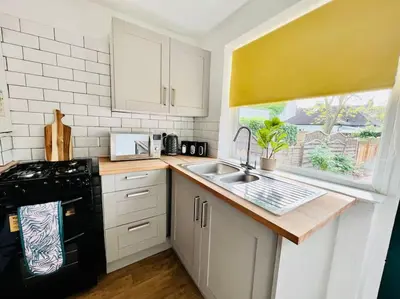 a kitchen with a sink and a black stove at Deluxe Apartment in Southend-On-Sea by Artisan Stays I Free Parking I Sleeps 5 in Southend-on-Sea