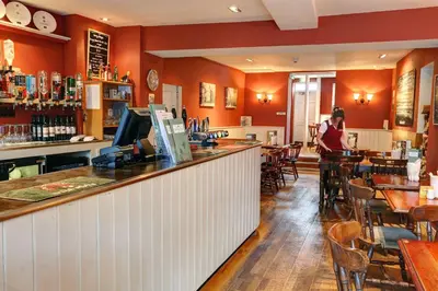 a woman standing at a bar in a restaurant at Best Western The George Hotel, Swaffham in Swaffham