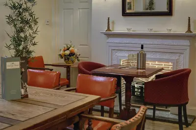 a dining room with a table and chairs and a fireplace at Best Western The George Hotel, Swaffham in Swaffham