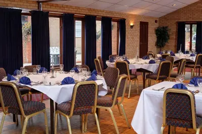 a room with tables and chairs with blue napkins at Best Western The George Hotel, Swaffham in Swaffham