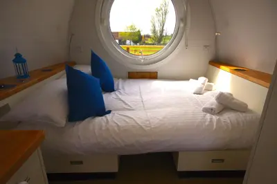 a bedroom with a large white bed with a window at Armadilla 2 at Lee Wick Farm Cottages & Glamping in Clacton-on-Sea