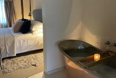 a bedroom with a bathtub next to a bed at Blacksmith's Cottage Suffolk in Lavenham