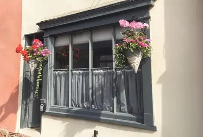 a window with two baskets of flowers on it at Blacksmith's Cottage Suffolk in Lavenham
