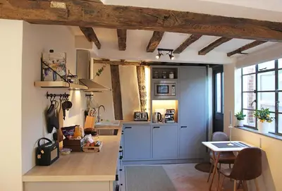 a kitchen with blue cabinets and a table in it at Blacksmith's Cottage Suffolk in Lavenham