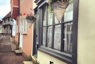 a building with a window with flower baskets on it at Blacksmith's Cottage Suffolk in Lavenham