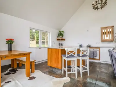a kitchen with white walls and a wooden table and chairs at Polly's Annexe in Ipswich