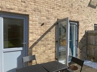 a door and a bench next to a brick wall at Warm & Cosy Homely 4 BDR Chesterton House w High Speed WIFI, Big Garden & Free Parking in Cambridge