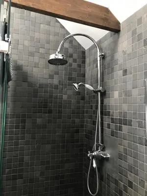 a shower in a bathroom with black tiles at Garden View in Saxlingham Thorpe