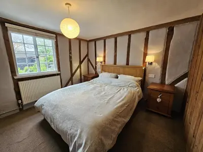 a bedroom with a large bed and a window at Perfectly Located Pretty Cottage in Diss