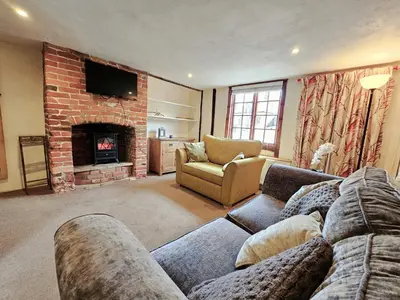 a living room with a couch and a fireplace at Perfectly Located Pretty Cottage in Diss