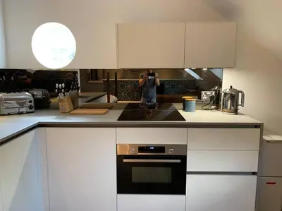 a kitchen with white cabinets and a person taking a picture at Scholar's Loft - Cosy & Close to Central Cambridge in Cambridge