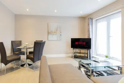 a living room with a tv and a table at Velvet 2-bedroom apartment, Conduit Lane, Hoddesdon in Hoddesdon