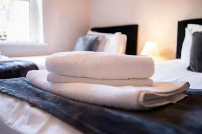 a pile of towels sitting on top of a bed at Velvet 2-bedroom apartment, Conduit Lane, Hoddesdon in Hoddesdon