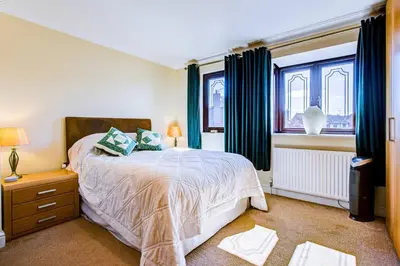 a bedroom with a bed and two windows at Serene Family Escape - Spacious, Near Thorpe Bay and Southend, Beaches & Amenities - Pass the Keys in Southend-on-Sea