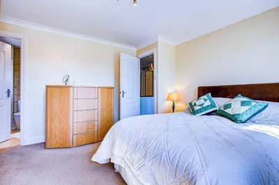 a bedroom with a large bed and a wooden cabinet at Serene Family Escape - Spacious, Near Thorpe Bay and Southend, Beaches & Amenities - Pass the Keys in Southend-on-Sea