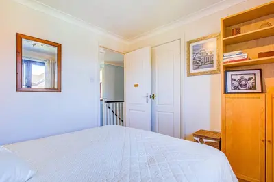 a bedroom with a white bed and a staircase at Serene Family Escape - Spacious, Near Thorpe Bay and Southend, Beaches & Amenities - Pass the Keys in Southend-on-Sea