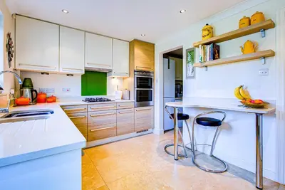 a kitchen with white cabinets and a counter with stools at Serene Family Escape - Spacious, Near Thorpe Bay and Southend, Beaches & Amenities - Pass the Keys in Southend-on-Sea