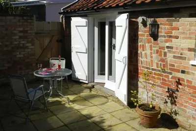 a patio with a table and a white door at The Old Dairy, Valley Farm, Middleton in Middleton