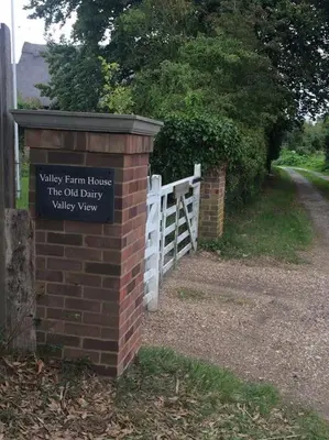 a brick wall with a sign on it next to a fence at The Old Dairy, Valley Farm, Middleton in Middleton