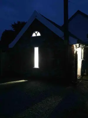 a house with a window with a light in the dark at The Old Dairy, Valley Farm, Middleton in Middleton