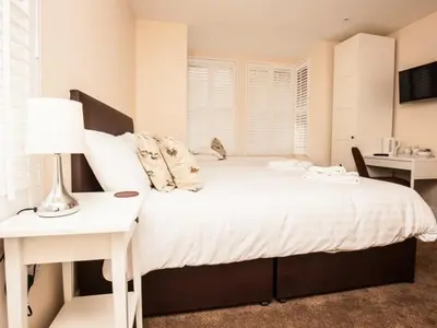 a bedroom with a white bed with a desk and a lamp at Bridge Hotel Brandon in Brandon