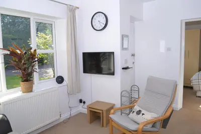 a living room with a chair and a clock on the wall at Beautiful studio in Ely in Ely