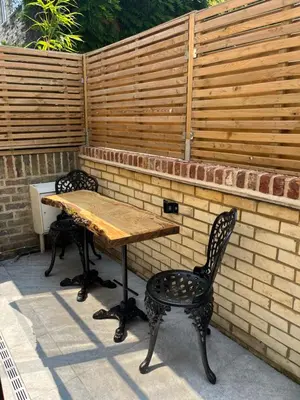 a wooden table and chairs in front of a brick wall at Emery Street Lodge in Cambridge
