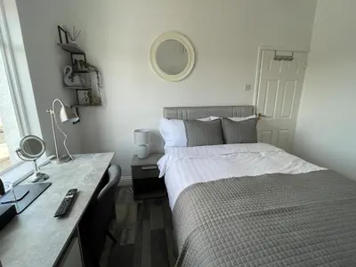 a bedroom with a bed and a desk with a mirror at Isabella Rooms in Hockley
