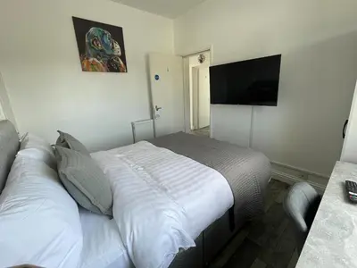 a bedroom with a bed and a flat screen tv at Isabella Rooms in Hockley