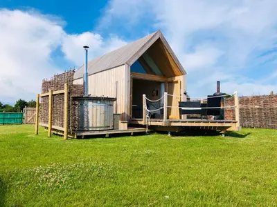 a small wooden house in a field of grass at Lushna 1 Mezzanine at Lee Wick Farm Cottages & Glamping in Clacton-on-Sea