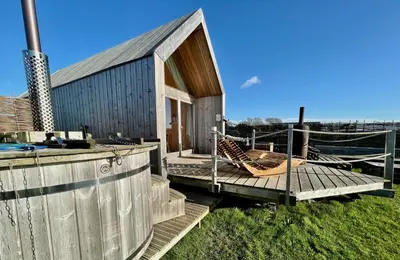 a building with a deck with a hammock on it at Lushna 1 Mezzanine at Lee Wick Farm Cottages & Glamping in Clacton-on-Sea