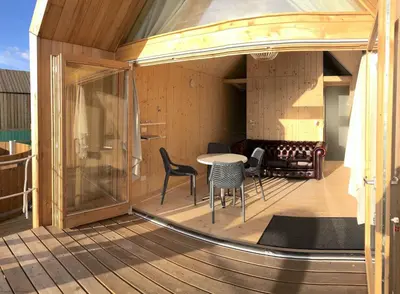 a patio with a table and chairs on a deck at Lushna 1 Mezzanine at Lee Wick Farm Cottages & Glamping in Clacton-on-Sea