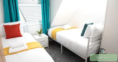 two beds in a small room with a window at 4-5 Bedroom House Garden Lots of Parking 15 min to city Close to motorway in Girton