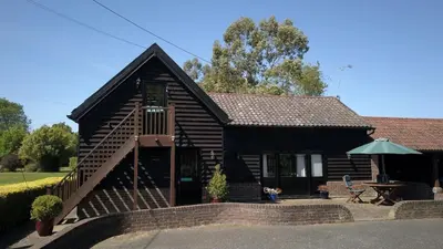 a log cabin with a table and an umbrella at Owls Nest - Peace and Tranquility near Woodbridge & Framlingham in rural Suffolk in Woodbridge