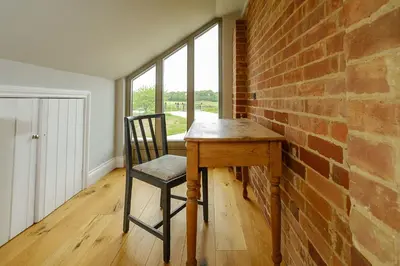 a wooden table with a chair next to a brick wall at Alde Bay Farm - Lobster Pot in Aldeburgh