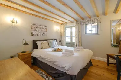 a bedroom with a large bed with white sheets at Alde Bay Farm - Lobster Pot in Aldeburgh