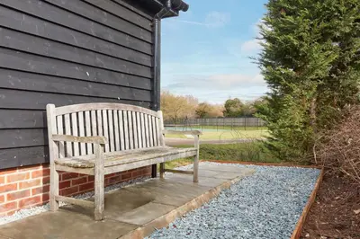 a wooden bench sitting next to a building at The Lodge Bury St Edmunds in Bury Saint Edmunds