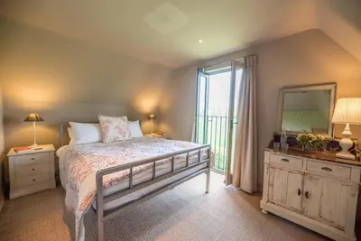 a bedroom with a bed and a mirror and a window at Gardiners Cottage Barn, Braiseworth in Eye
