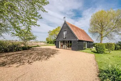 a small black church with a cross on the roof at Gardiners Cottage Barn, Braiseworth in Eye