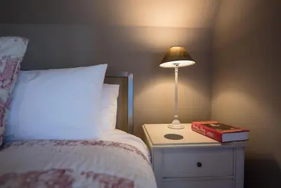 a bed with a lamp and a book on a night stand at Gardiners Cottage Barn, Braiseworth in Eye