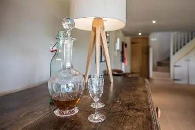 a table with two glasses of wine and a lamp at Gardiners Cottage Barn, Braiseworth in Eye